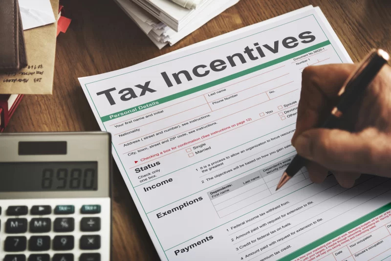 Person filling a Tax Incentive form with a calculator next to it